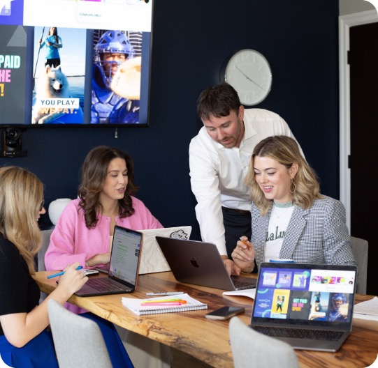 A franchise development team collaborating at a table with laptops.