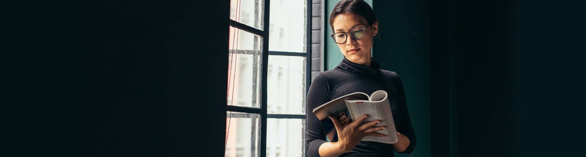 photo of a customer standing by a window reading a magazine with PR announcements