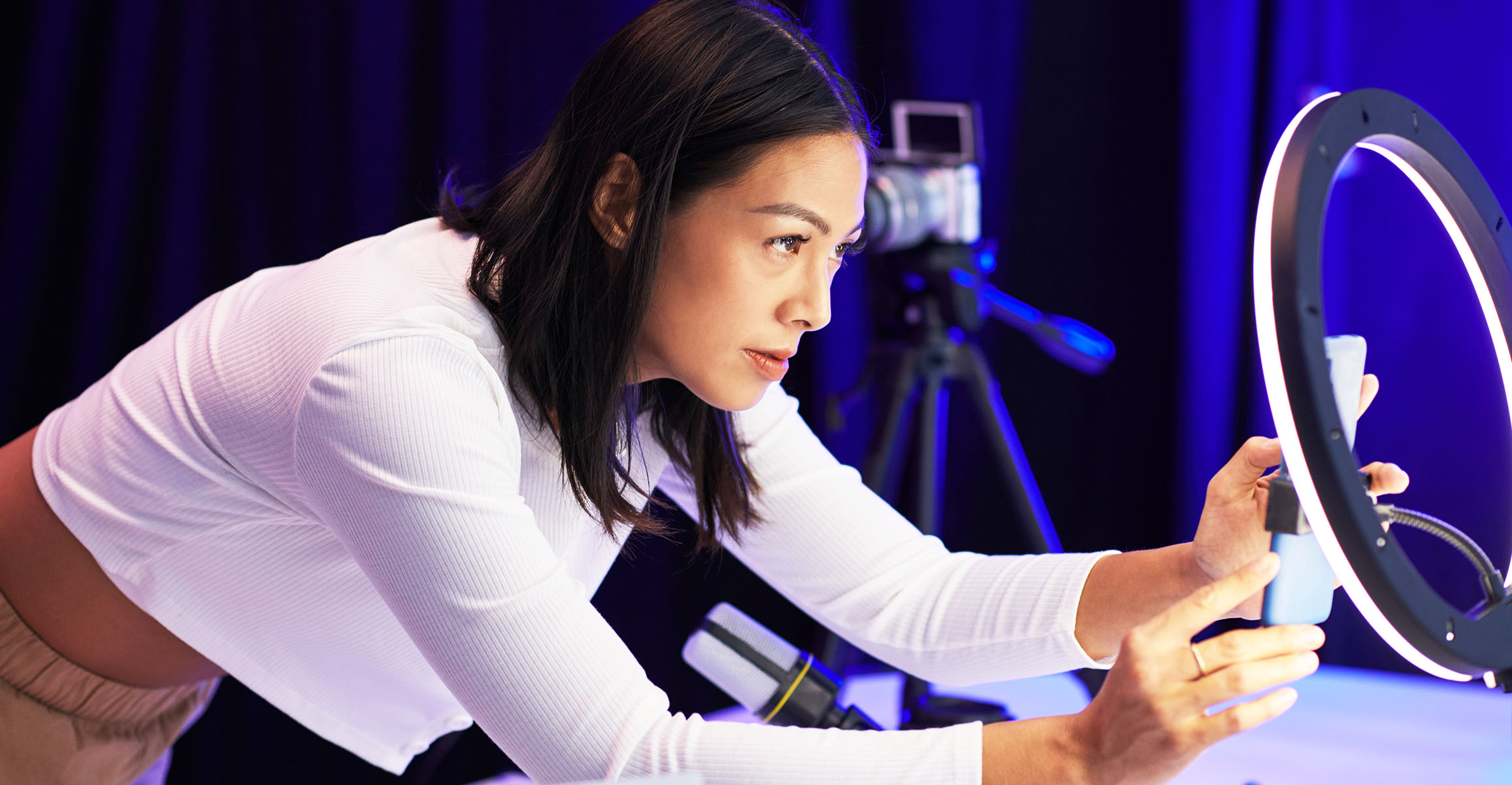 Woman setting up a cell phone in front of a ring light for video